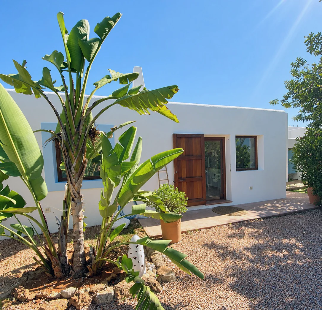 Fachada blanca y jardín mediterráneo de la finca