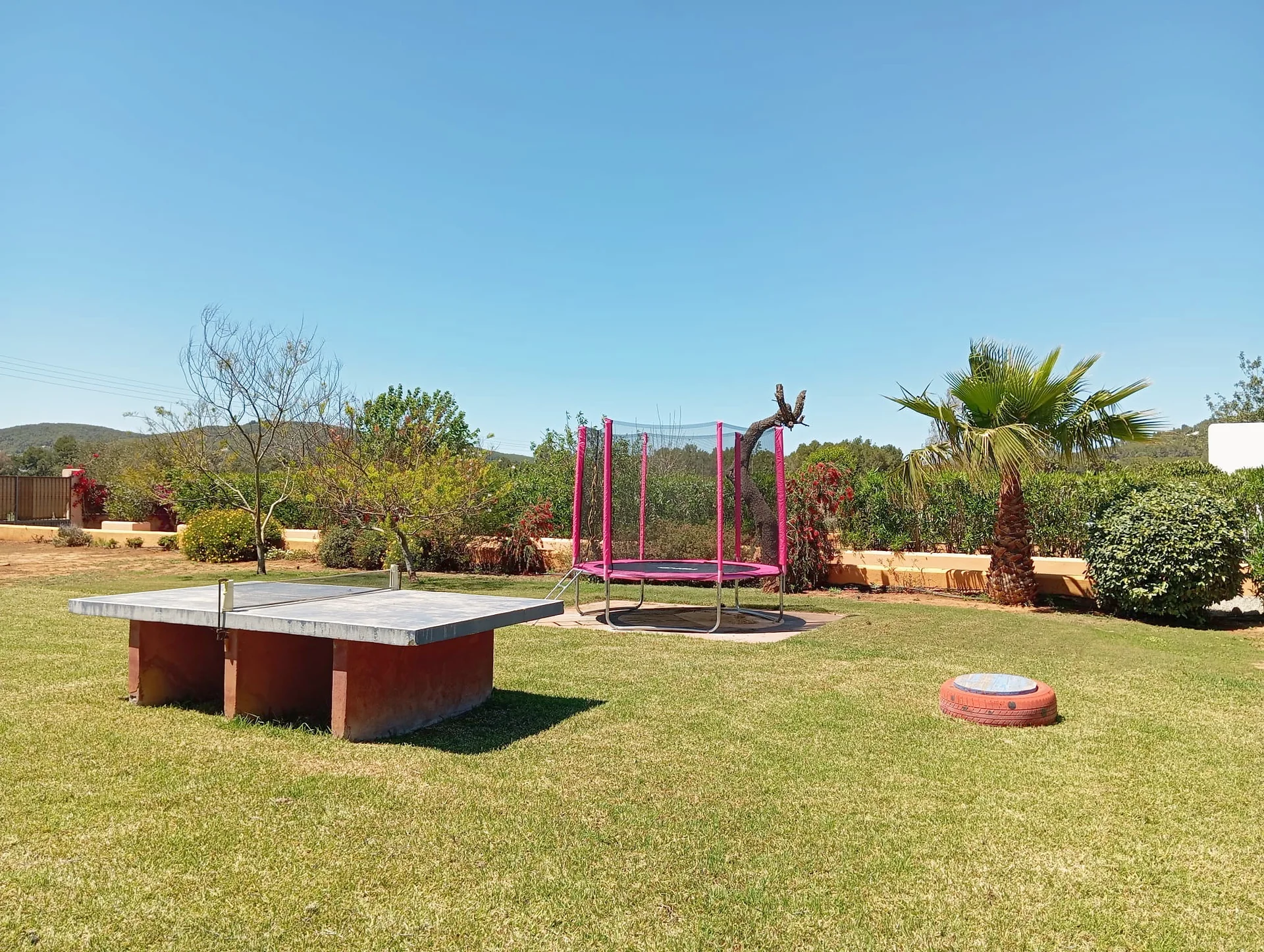 Zona infantil con mesa de ping-pong y cama elástica